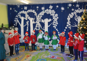 Dzieci z grupy Pszczółki, przebrane za Elfy i Mikołaje, śpiewają piosenkę..